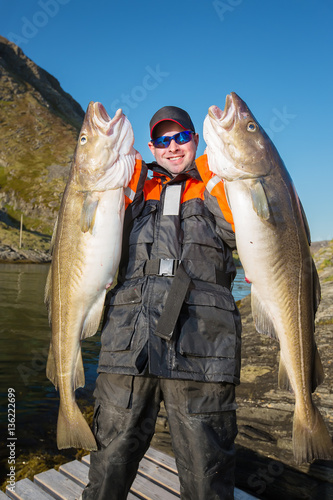 Happy fisherman pokazyvaetes two big fish in their hands. Vertic