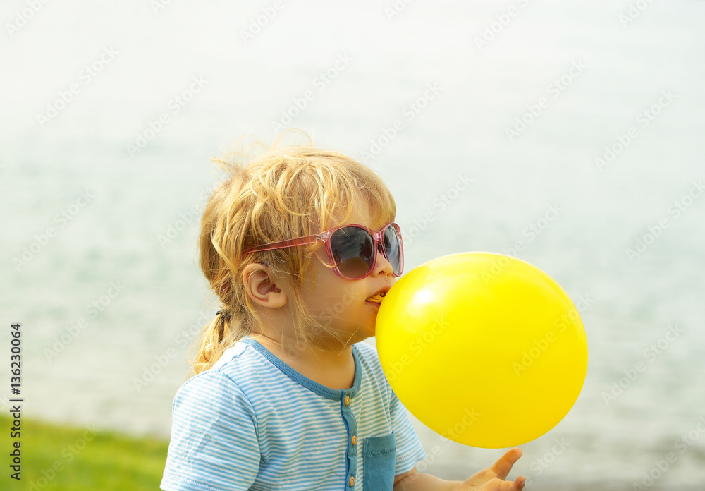 Cute baby boy plays with yellow toy balloon Cute baby boy plays with yellow toy balloon
