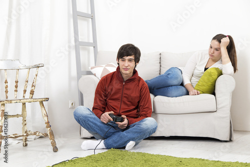 Young man playing video games and girlfriend bored beside © nikodash
