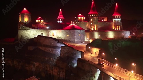 Old castle with red illumination at night, is former Ruthenian-Lithuanian castle and a later Polish fortress, located in historic city of Kamianets-Podilskyi, in historic region of Podolia in Ukraine photo