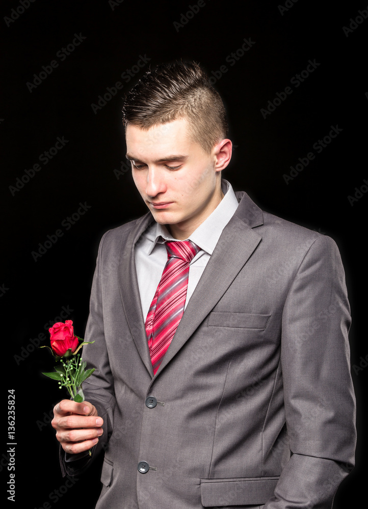 Young man holding red roses in beautiful suit and red tie Young man holding red roses in beautiful suit and red tie