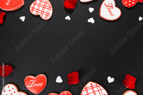 Beautiful gingerbread heart and red petals roses on a black background. Postcard for Valentine's day, March 8, mother's day or Wedding. Free space for text