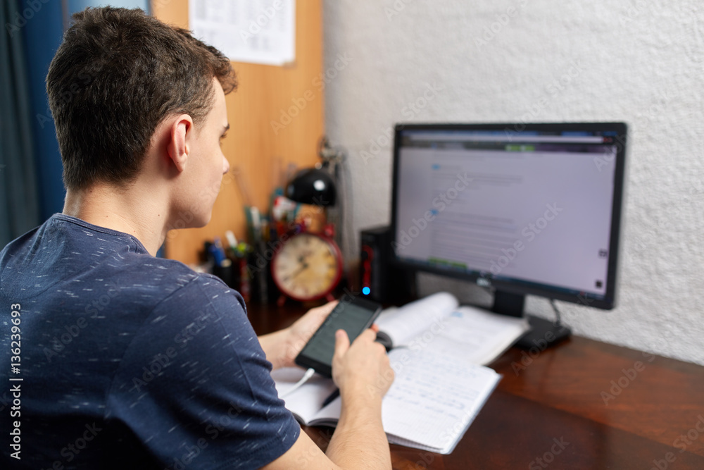 Teenager doing homework with computer Teenager doing homework with computer