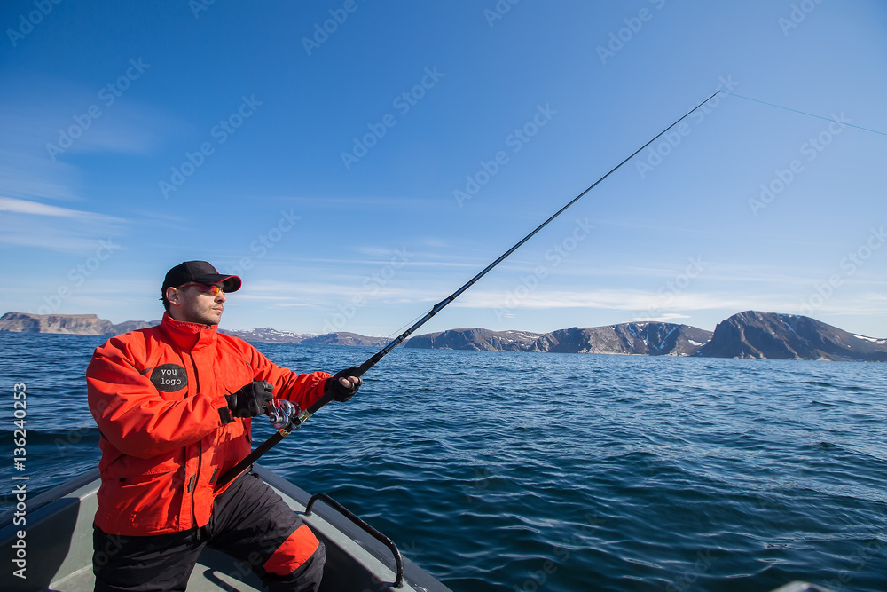 Fisherman athlete with a fishing rod in his hands. boat. sea Fisherman athlete with a fishing rod in his hands. boat. sea