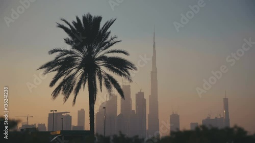 Wallpaper Mural Sunset in Dubai: Palm silhouette of the Burj Khalifa and other skyscrapers, past the camera passing cars. Sunrise Sunset Tall Building Burj in Dubai. Skyline Cityscape City Torontodigital.ca
