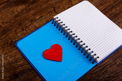 Red heart on the open blank notebook. Valentines day concept with empty notepad. Womens diary. Love design. Wooden rustic board.
