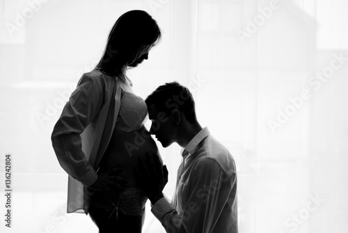 Obraz na płótnie Husband is kissing pregnant wife's tummy w salonie