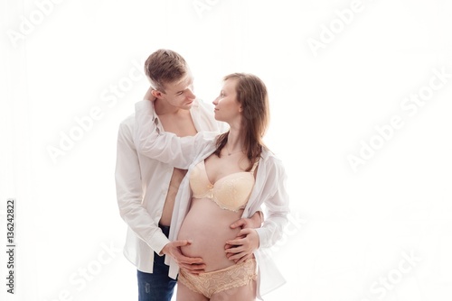 Pregnant woman with her husband on white background © Daniel Jędzura