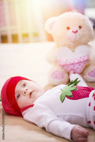 Wallpaper Mural Happy baby wearing strawberry shirt and pants. Newborn child relaxing in bed. Close up of a beautiful baby girl lying on the bed. Torontodigital.ca