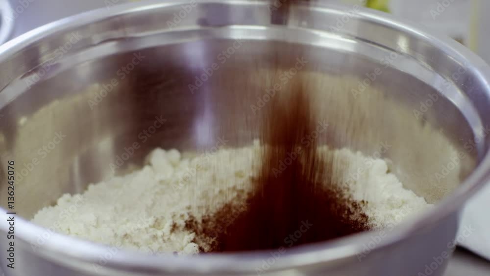 Woman hand adds the cocoa powder to the flour Woman hand adds the cocoa powder to the flour