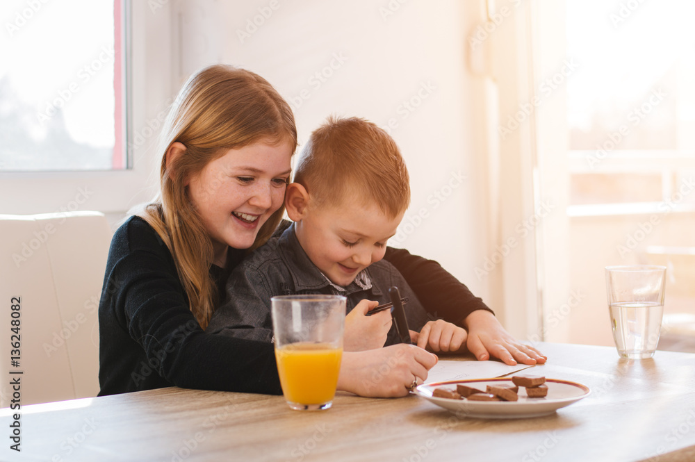 Happy little girl and her brother writting on paper. Lens flare Happy little girl and her brother writting on paper. Lens flare