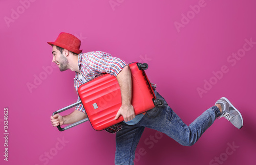 Man traveler with suitcase on color background photo