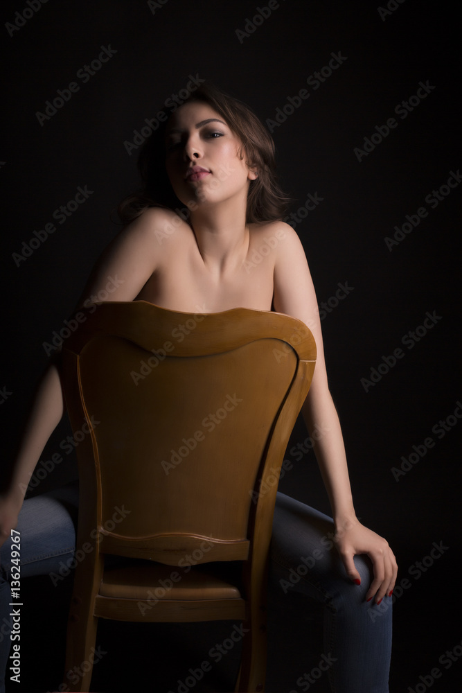 Glorious topless woman in blue jeans sitting on a chair Glorious topless woman in blue jeans sitting on a chair