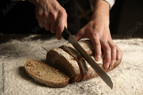 Male hands cutting homemade bread, closeup