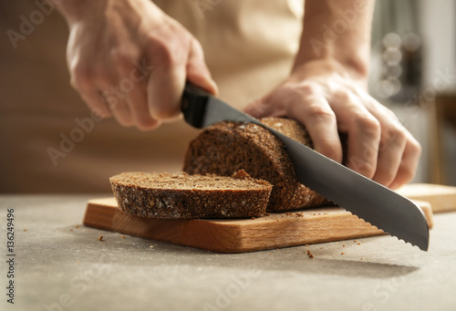 Male hands cutting homemade bread, closeup