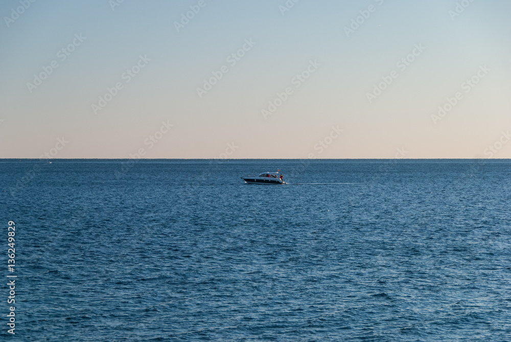 Lonely fishing boat at the open sea at sunset, freedom concept