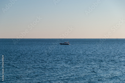 Lonely fishing boat at the open sea at sunset, freedom concept © Neeqolah