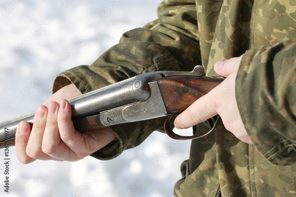 Fototapeta premium Close-up of a hunter holding his old 16 caliber side-by-side double-barreled shotgun in winter forest