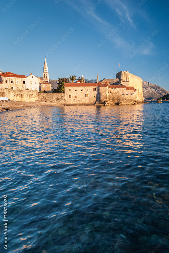 Ancient stone buildings by the sea at sunset in old town Budva, Montenegro