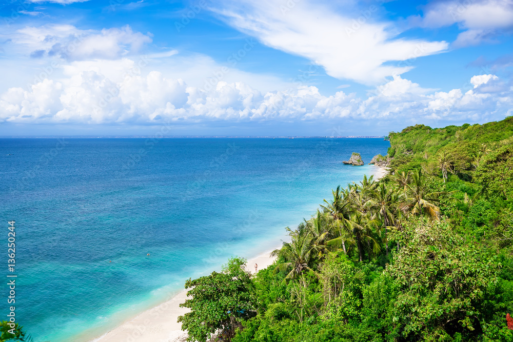 Tropical beach and ocean in Bali. Blue sky, blue water. Tropical jungle