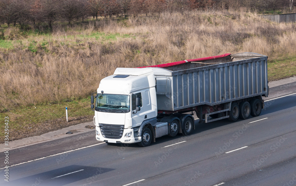 White lorry with tipping trailer in motion on the motorway
