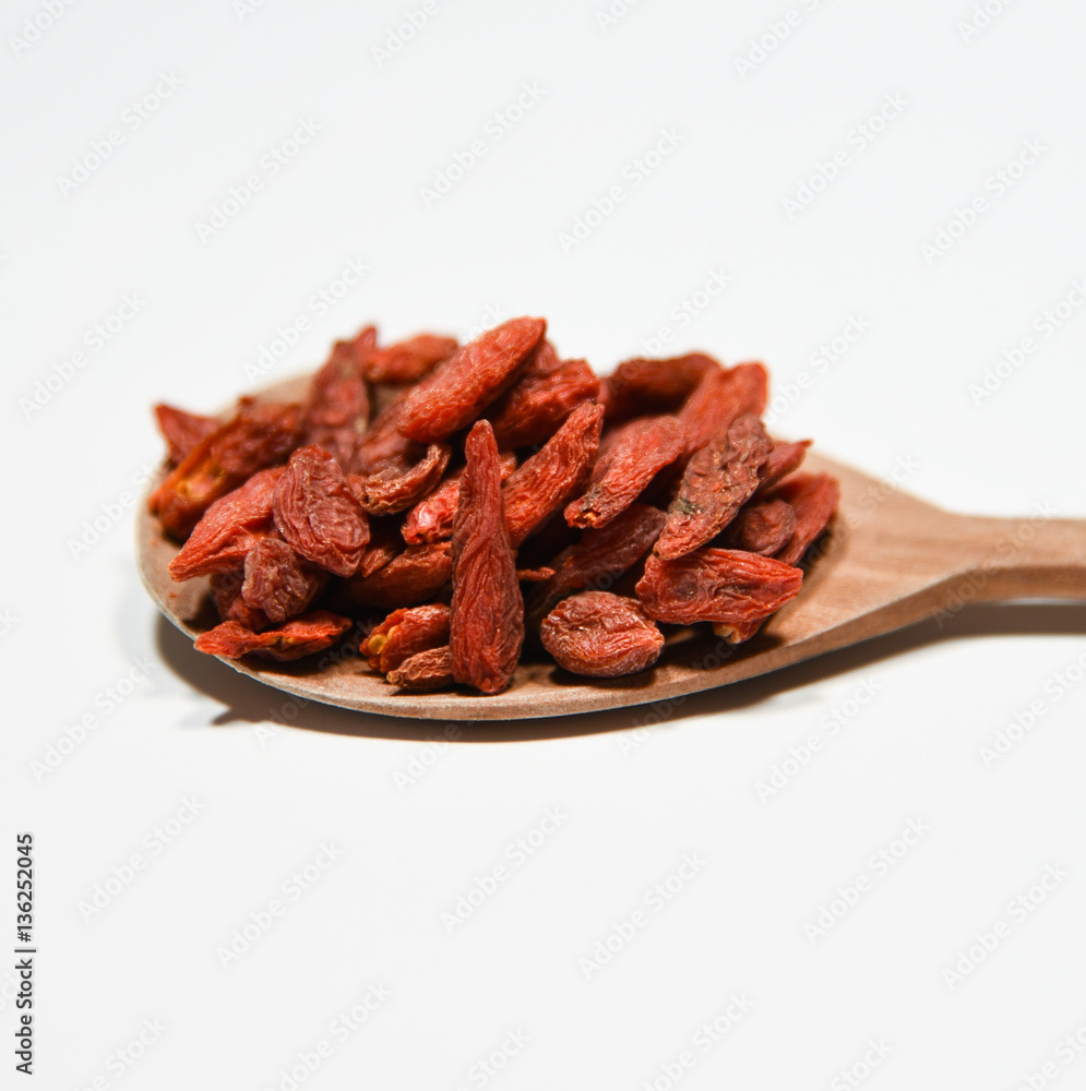 red dried goji berry fruit on decorative wooden spoon on white background close up red dried goji berry fruit on decorative wooden spoon on white background close up