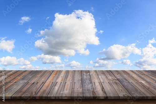 Empty wooden table with blue sky background.