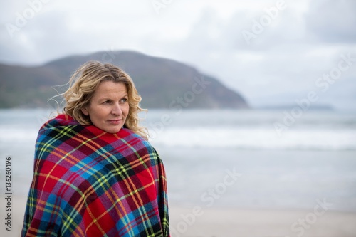 Mature woman wrapped in shawl on the beach