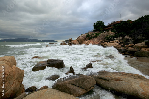 The South China sea off the Vietnamese coast near the city of Nha Trang. A cloudy day with rain clouds and the waves on the rocky coast in January day