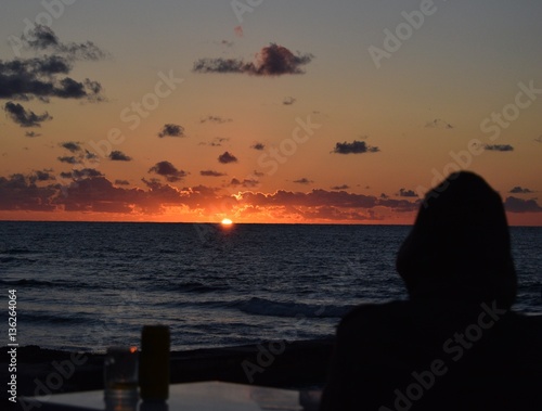 Silhouette of man having drink near sea at sunset