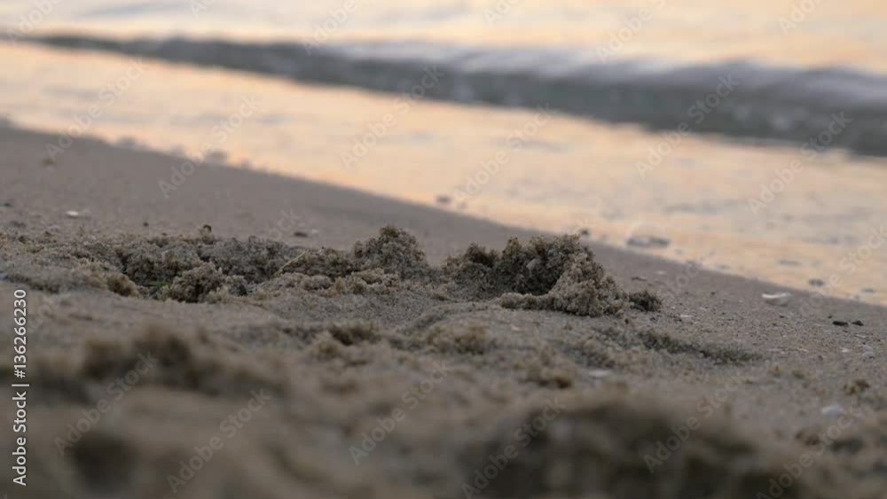 Close-up shot of beach sand and sea waves rolling on the shore at sunset Close-up shot of beach sand and sea waves rolling on the shore at sunset