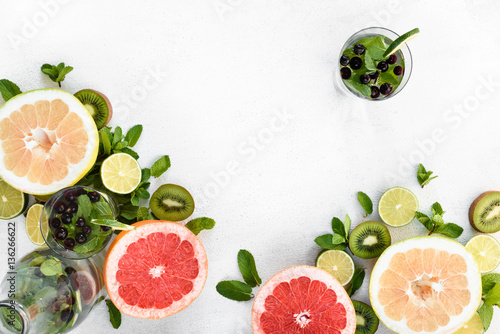 Grapefruit, limes and kiwis pieces on white top view with drinks