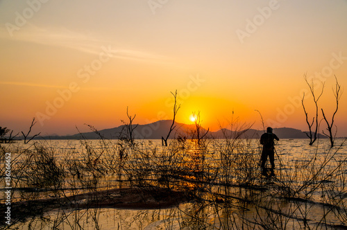 Silhouette Dry tree and Photographer in water at Bang Phra Reservoir Sriracha,Chonburi, Thailand.