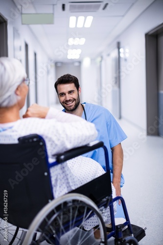 Male doctor interacting with senior patient on wheelchair