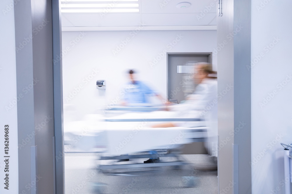 Doctors and nurse pushing emergency stretcher bed in corridor Doctors and nurse pushing emergency stretcher bed in corridor