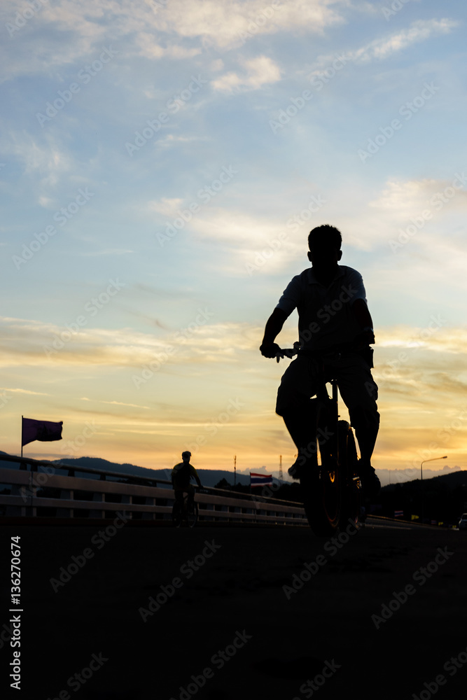 silhouette of young man  cyclist on sunrise sky with clouds