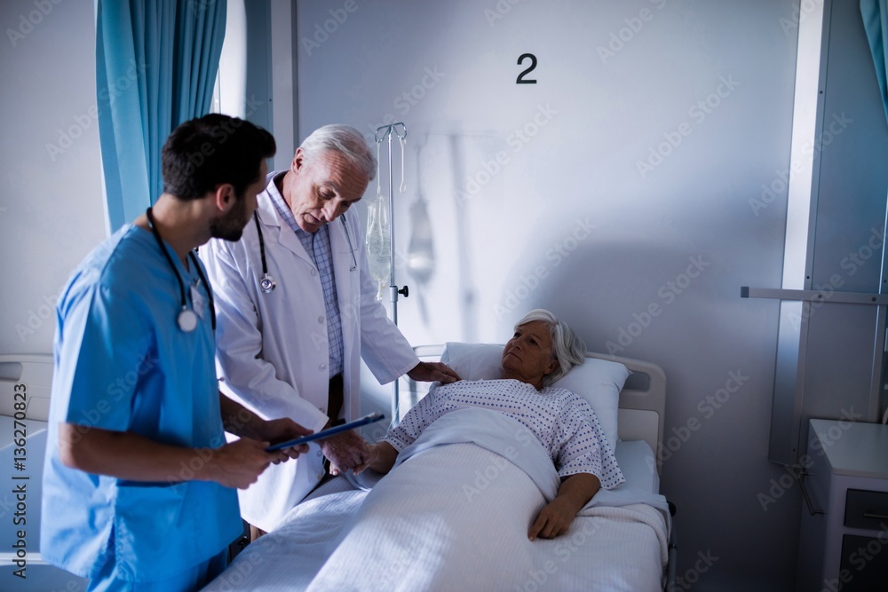 Obraz premium Doctors comforting senior patient on bed