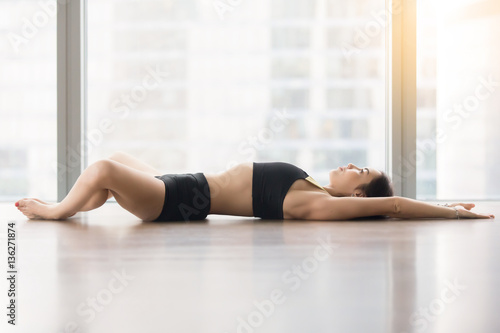 Fényképezés Young sporty woman practicing yoga, lying in Reclined Butterfly exercise, supta