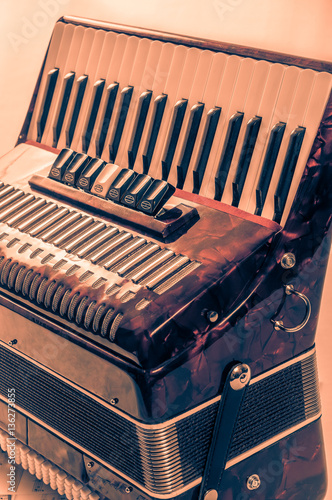 part red musical instrument accordion, white background photo