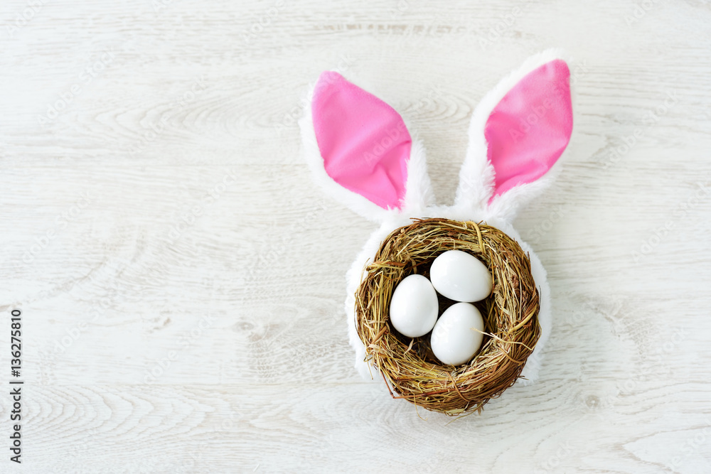 A nest with three white Easter eggs and bunny ears at home on Easter day A nest with three white Easter eggs and bunny ears at home on Easter day