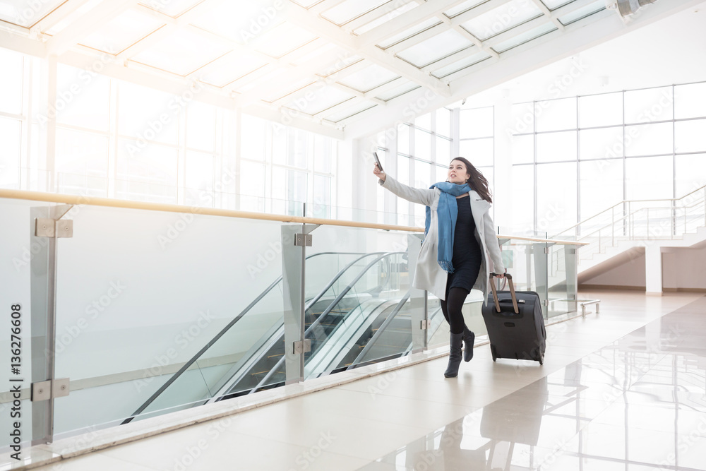 Fototapeta premium Young business woman with suitcase running to catch the plane