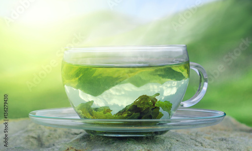 Green tea time. Green tea leaves at the bottom of the cup. Green tea on a background of mountains. Hot tea.