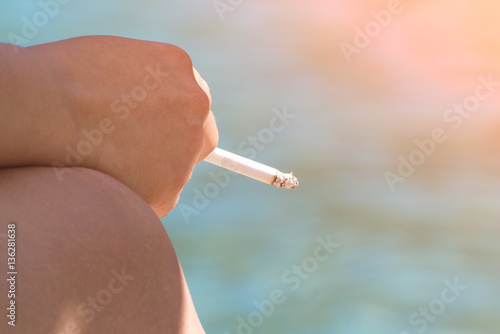 Woman with a cigarette near sea in the sunlight