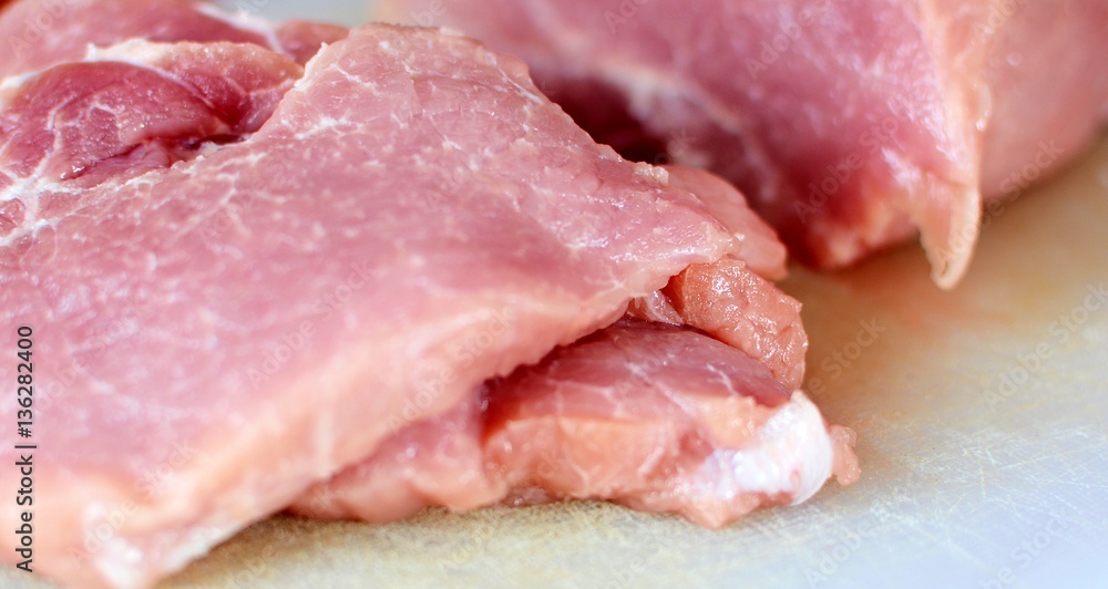 Raw pork meat slices on white cutting board. Raw pork meat slices on white cutting board.