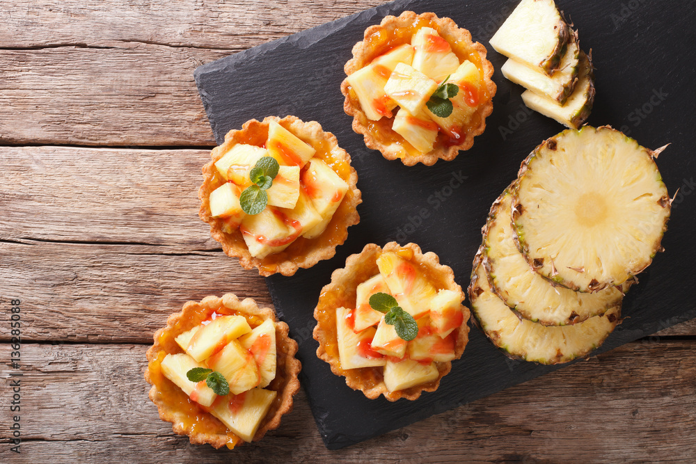 Delicious tartlets with fresh pineapple and jam closeup on the table. horizontal top view