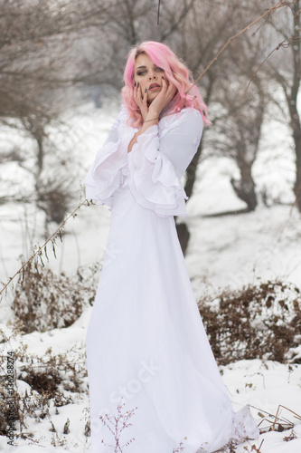 Winter portrait of a yong sensual girl in white dress at the snow forest.