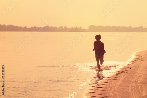 Teen girl running on the water at sunset
