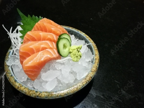 Special Deluxe salmon sashimi set on ice sever with wasabi and cucumber , traditional Japanese food with space, focus salmon with blur backgroup