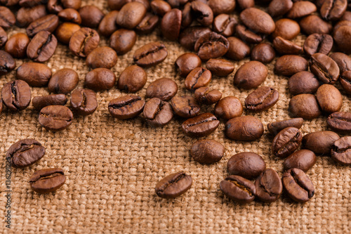 Fototapeta Naklejka Na Ścianę i Meble -  coffee beans on burlap background. roasted coffee beans isolated in white background. Roasted coffee beans background close up. Coffee beans pile from top on white background with copy space for text