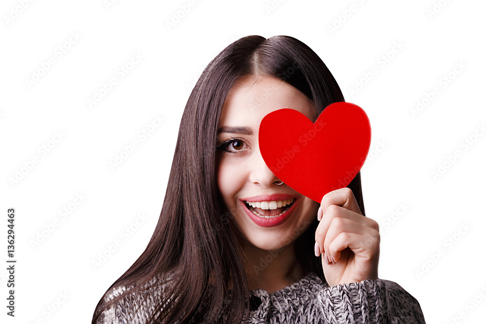 Attractive smiling woman keeping paper red heart by one eye. Studio portrait isolated on white background. Surprising woman in love concept. Attractive smiling woman keeping paper red heart by one eye. Studio portrait isolated on white background. Surprising woman in love concept.
